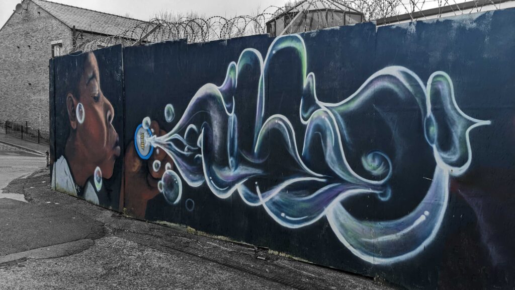 Graffiti Painting of a girl blowing bubbles which turn into graffiti letters